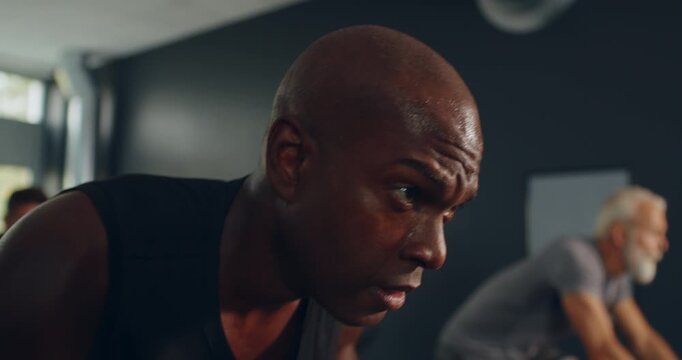 Fit young black man in sportswear doing a
cycling class with a group of diverse
people at the gym