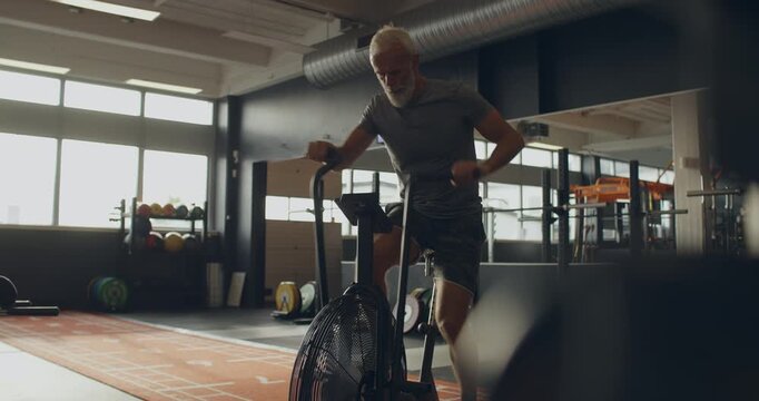 Fit mature man in sportswear working
out on a stationary bike while
exercising at the gym