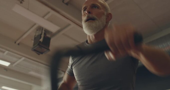 Low angle view of a fit mature man in
sportswear working out using a
stationary bike in a gym