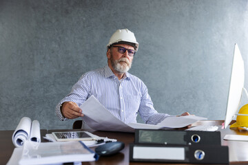 Senior engineer ponders construction plans in office