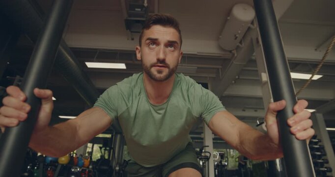 Fit young man in sportswear pushing
a sled across the floor of a gym
during a workout session