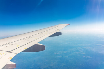 Fototapeta premium View from the airplane window at a beautiful blue clear sky and the airplane wing
