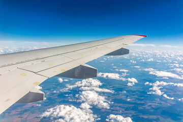 Obraz premium View from the airplane window at a beautiful cloudy sky and the airplane wing