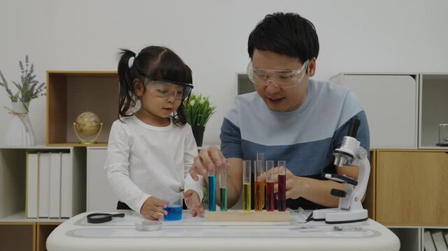 father and toddler girl scientist making chemical test with test tube. learning science at home