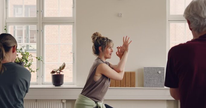 Yoga teacher leading a mixed age range group
of students through the eagle pose during a
beginners yoga class