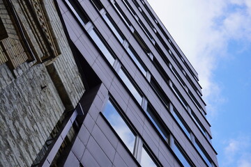 Modern architecture showcases reflections on glass facade under a clear blue sky in an urban setting