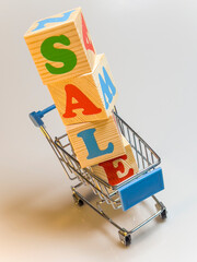 A wooden shopping cart is piled high with blocks SALE.