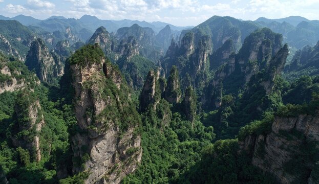 Lush green mountain peaks, dramatic rock formations, valleys, and hazy clouds