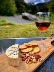 Glass of Red Wine and a Cheese Board by a River