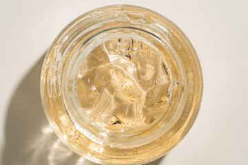 24k gold skin care cream gel in a glass jar close up. Beauty treatment product texture macro