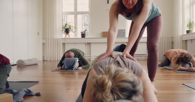 Instructor helping a student using a bolster
pillow for support with her child's pose during a
beginners yoga class in a studio