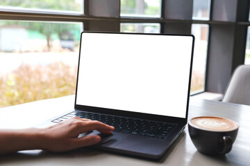 Mockup image of a woman working and typing on laptop computer with blank white desktop screen in...