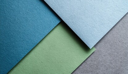 Abstract geometric shapes of overlapping textured papers in shades of blue, green, and gray