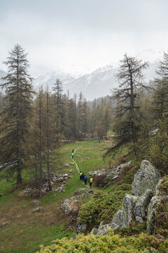 A group of hikers crossing a rainy valley in the Alps