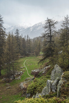 A hiker crossing a rainy valley in the Alps