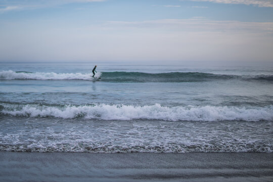Surfer riding ocean wave with sand and blue sky at beach