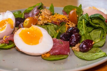 Boiled eggs with spinach, nuts, tomatoes, cheese, seasoned with pepper and salt and drizzled with olive oil.