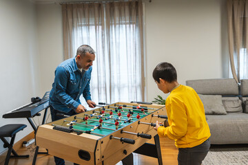 Father and son enjoying a game of table football in their living room, spending quality time together