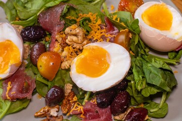 Boiled eggs with spinach, nuts, tomatoes, cheese, seasoned with pepper and salt and drizzled with olive oil.