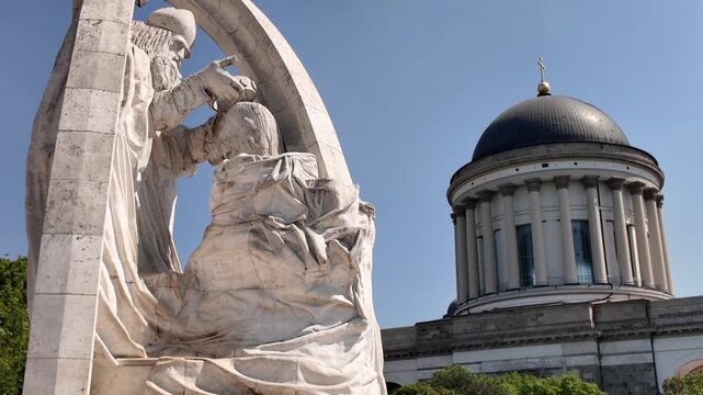 Statue of Saint Stephen I of Hungary baptizing Vajk, the first King of Hungary, located in Esztergom, Hungary, with the Esztergom Basilica in the background under a clear blue sky