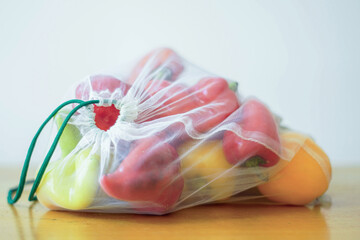 Colorful bell peppers in a reusable mesh bag. Vegetables in eco-friendly packaging with care for the environment. The concept of green living, waste reduction, and sustainable shopping alternatives