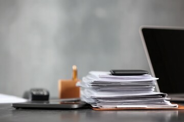 close-up of a desk in an office with documents, a laptop, and a phone on it, against a gray background, minimalistic style.