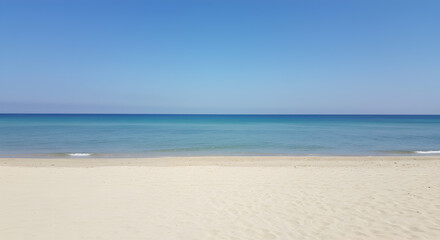 Obraz premium Calm Azure Sea Meets Sandy Beach on a Bright Sunny Day Under Clear Blue Sky