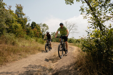Cyclists enjoying a scenic outdoor ride on dirt trails surrounded by lush greenery.