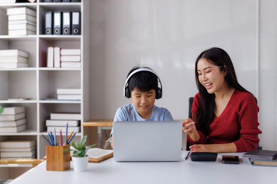 Asian teacher helping student with headphones using laptop in class