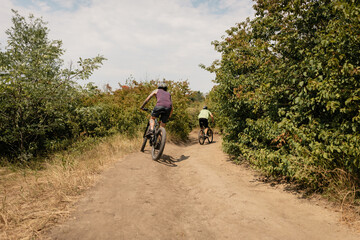 Cyclists enjoying a ride on outdoor trail surrounded by trees and nature beauty.