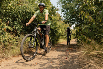 Two cyclists riding through a scenic forest trail in warm daylight