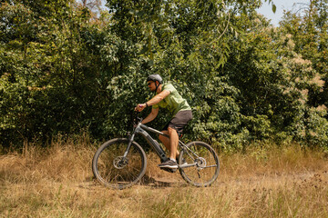 Man cycling on a scenic forest trail during a sunny summer day outdoors.