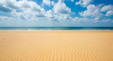 Obraz premium Wide Sandy Beach with Turquoise Water and Blue Sky with White Clouds at Sunny Day