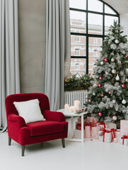 Modern living room with a large window on the right side. the window has white curtains and is letting in natural light. on the left side of the window, there is a red armchair with a white cushion.