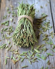 A rustic bundle of dried herbs tied with twine, surrounded by scattered leaves on a weathered wooden surface.