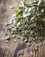 Dried oregano leaves piled on textured wooden surface, showcasing vibrant green hues and natural beauty.