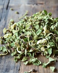 Dried oregano leaves scattered on a rustic wooden surface, showcasing a variety of shades and textures.