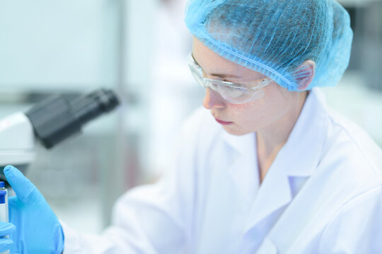 A molecular biologist performs a polymerase chain reaction PCR setup, using a calibrated micropipette to dispense a precise volume of reagent into a microplate well.