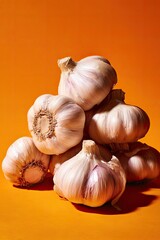 A stack of garlic bulbs against an orange backdrop