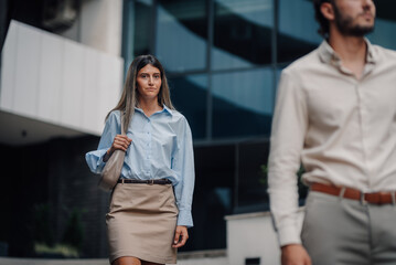 Businesswoman walking near office building with male colleague