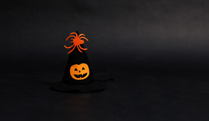 Witch hat decorated with orange spiders and pumpkin on black dark background ideal seasonal...