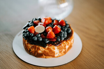 Delicious fruit-topped cheesecake on wooden table in modern kitchen setting