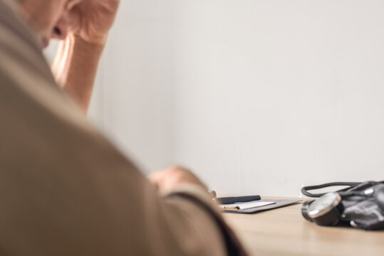 Confused man with health problems having high blood pressure. A man is seated at his desk, appearing deep in thought, as he reflects on various important matters of life