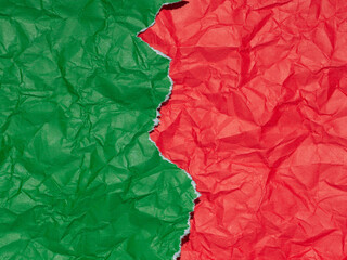 Crumpled torn green paper on red crumpled background, revealing a contrasting texture.