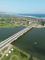 Fototapeta premium Special Region of Yogyakarta, Indonesia - September 3, 2025 : A Scenic Bridge Spanning a Wide River with Lush Green Surroundings