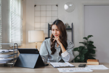 Asian businesswoman working from home using tablet and analyzing financial charts
