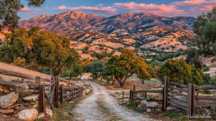 Serene sunset paints rolling hills, a dirt road leads through a rustic wooden fence towards a mountain range