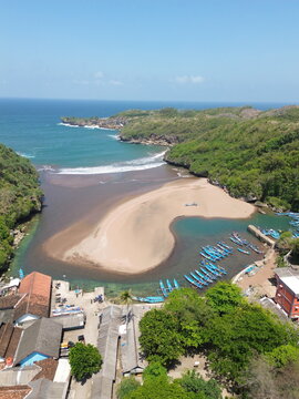 Scenic Coastal View with Lighthouse, Beach, Village, and Boats
