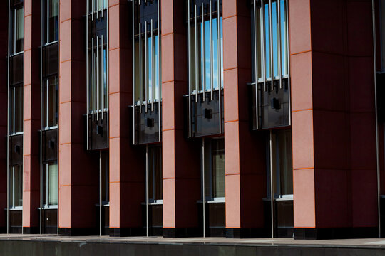 The building's fa&ccedil;ade features a contemporary style with vertical elements. Red panels alternate with large windows, creating a clean and minimalist look. Metal inserts add dynamism and accents.