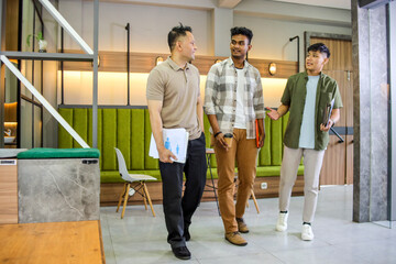 Men Walking and Having Casual Discussion in Modern Office Holding Papers and Coffee Cup